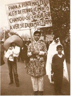 Cortejo dos anos 60: o cartaz de um Caloiro sobre a ponte que, «para durar mais, além de ferro e cimento, chamou-se-lhe Salazar».